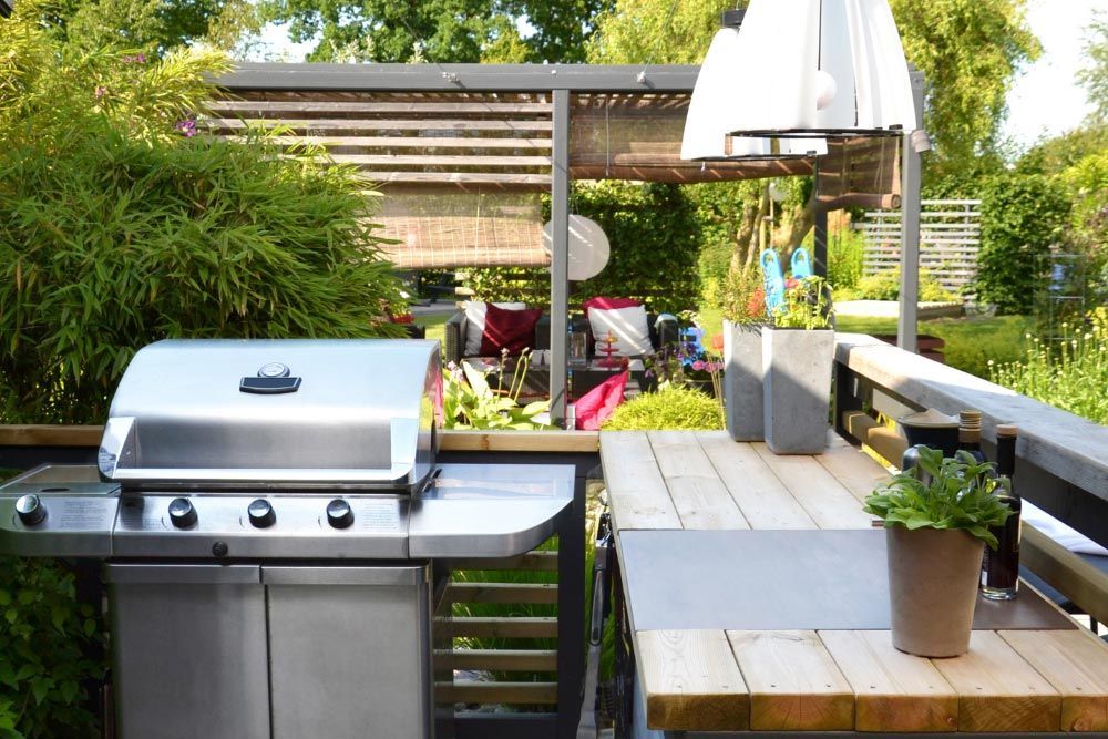A stainless steel grill is sitting next to a wooden table.