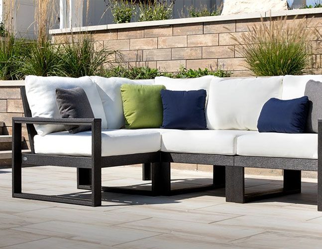 A sectional couch with white cushions and blue pillows on a patio