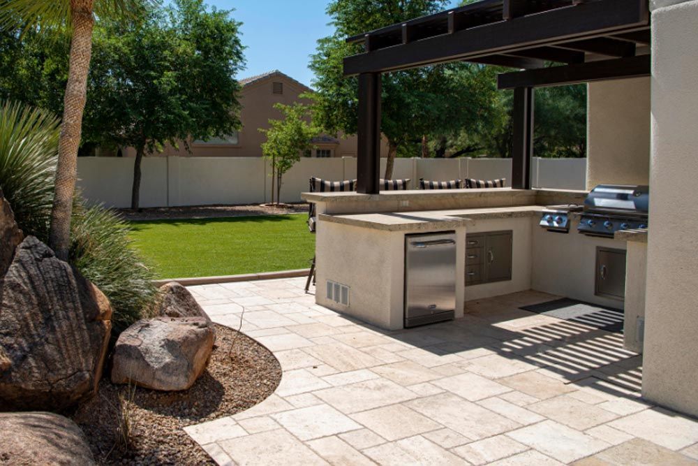 An outdoor kitchen with a grill , sink , and wooden fence.