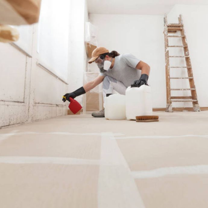 Mold Remediation Inc - A man wearing a mask is spraying something on the floor