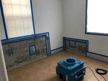 Mold Remediation Inc -A room with blue tape on the walls and a machine on the floor.