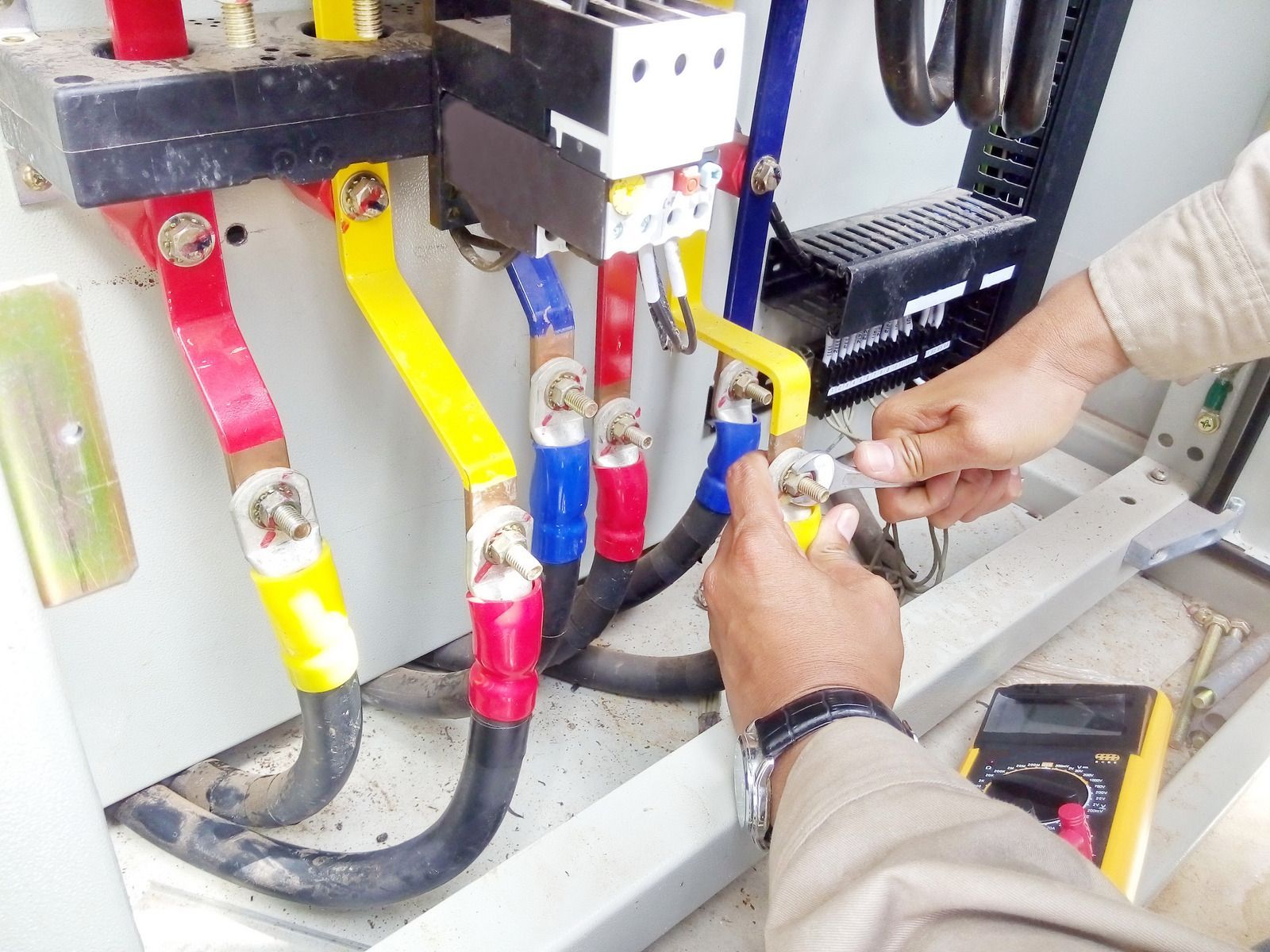 A man is working on an electrical box with a pair of pliers.