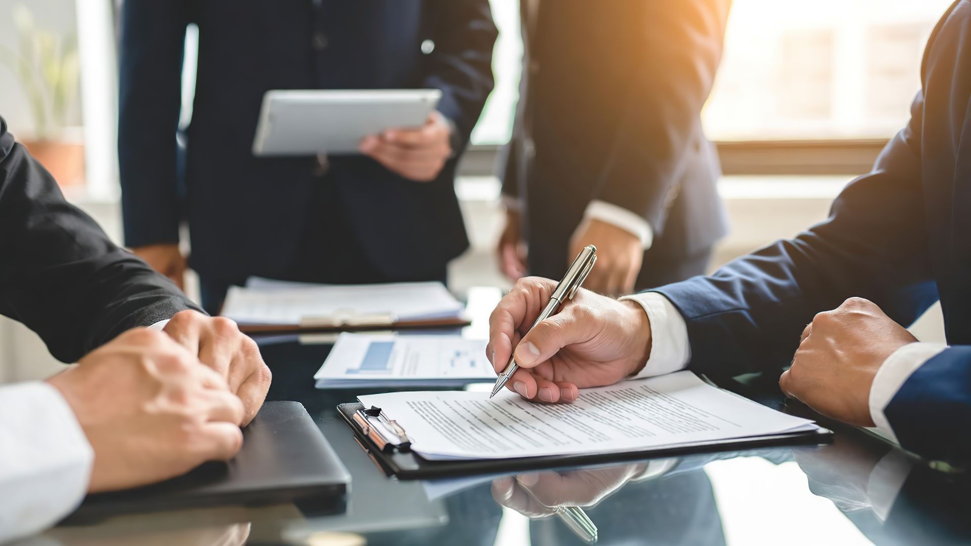 A businessman's hand signing an important official contract during a formal meeting.
