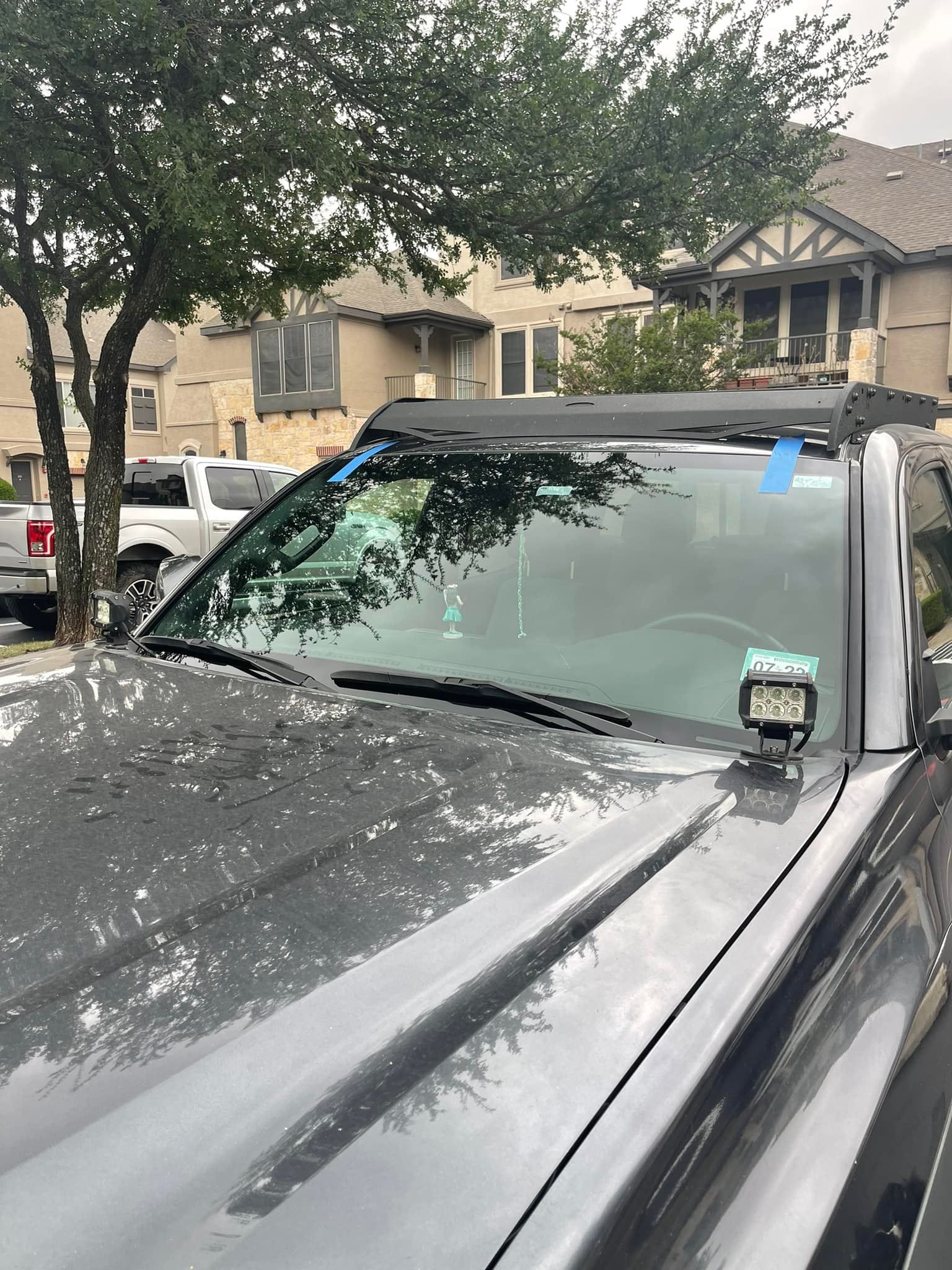 A truck with a roof rack on top of it is parked in front of a house.