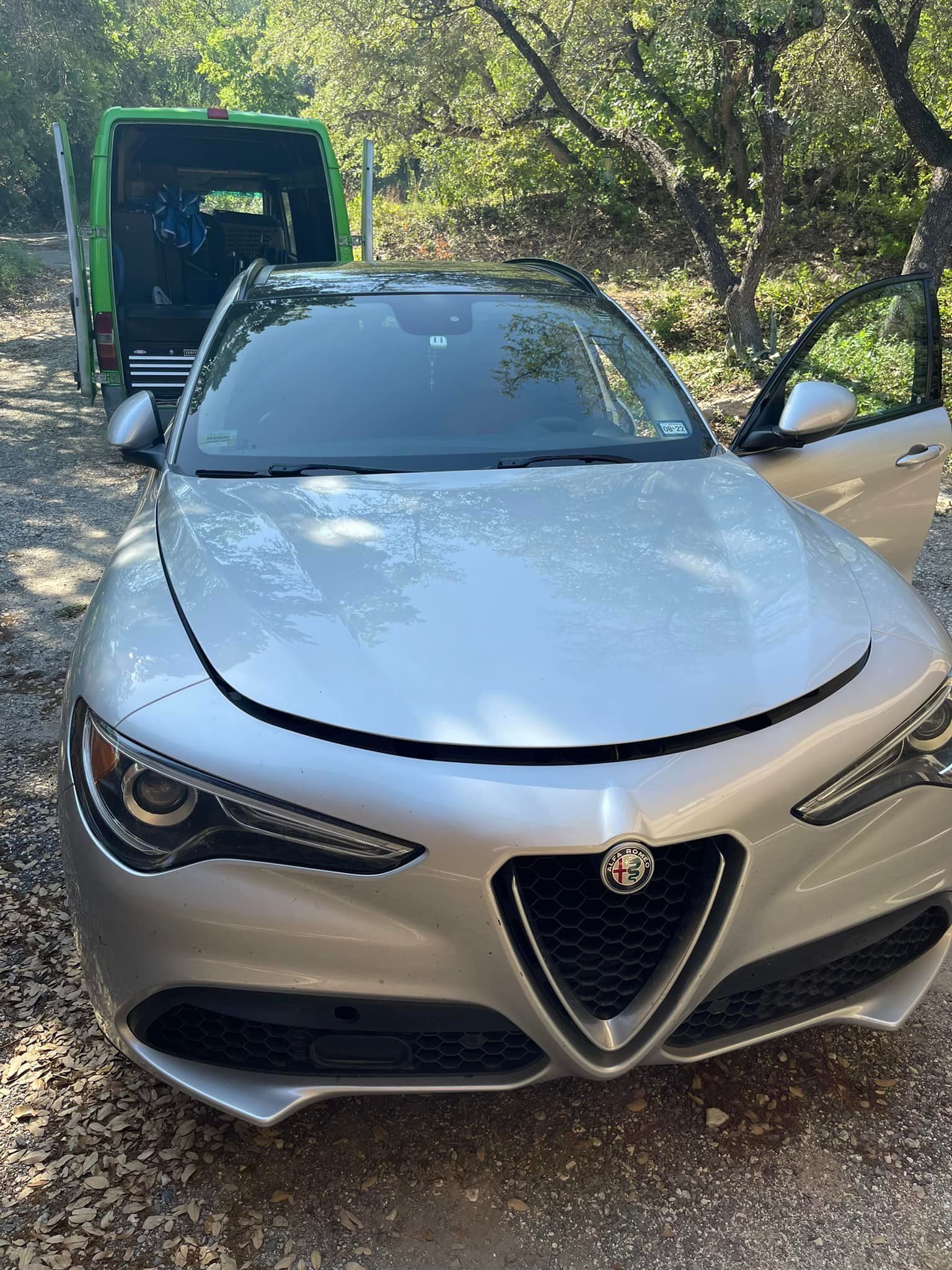 A silver car is parked on the side of a dirt road.