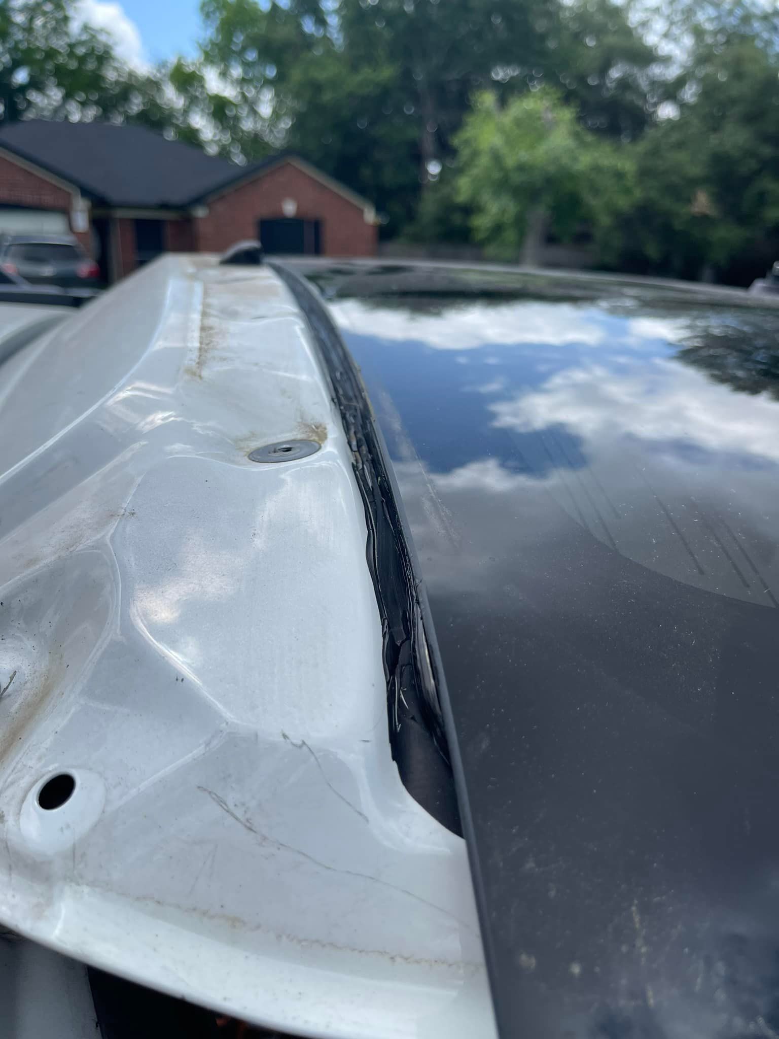 A close up of the roof of a car with a house in the background.