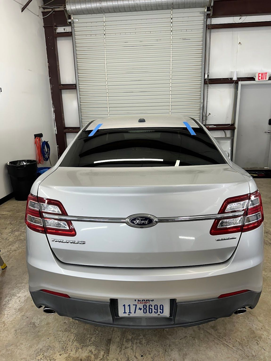 A silver ford taurus is parked in a garage.