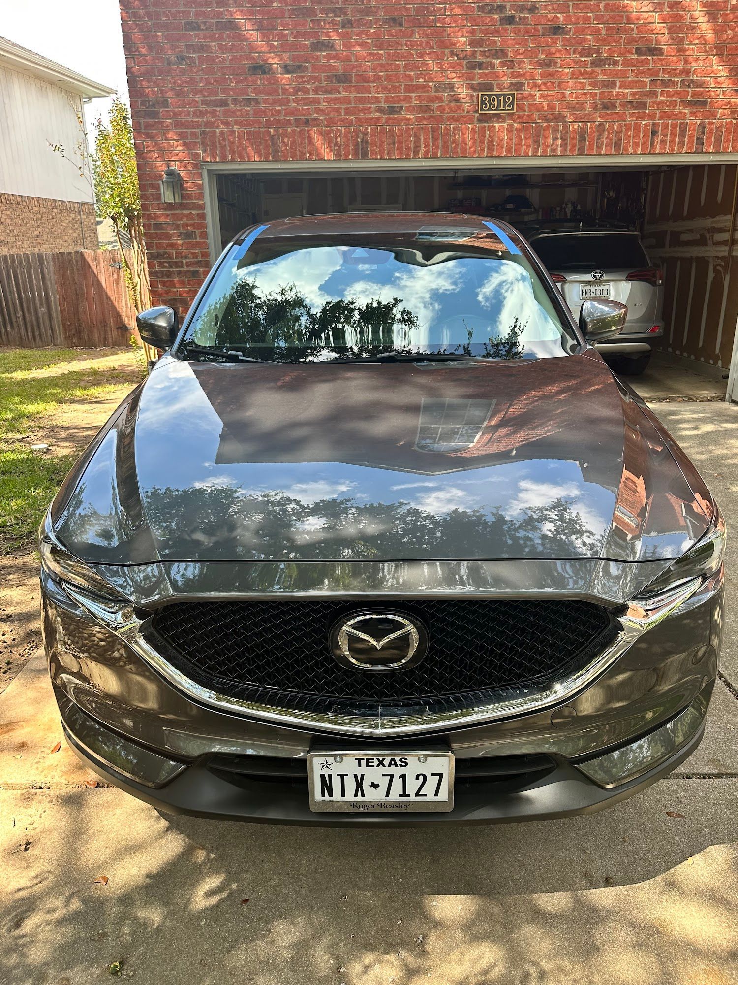 A black mazda cx 5 is parked in front of a brick garage.