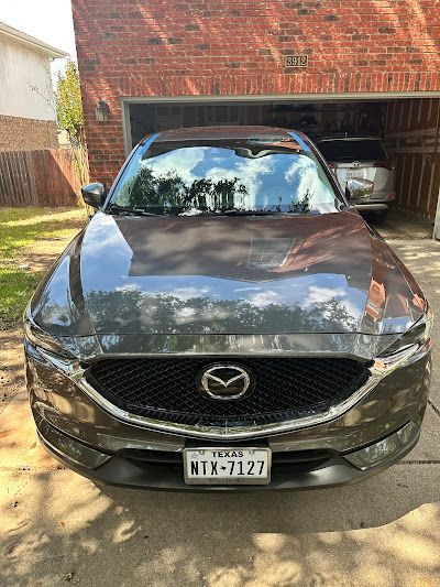 A mazda cx 5 is parked in front of a brick house in a driveway.