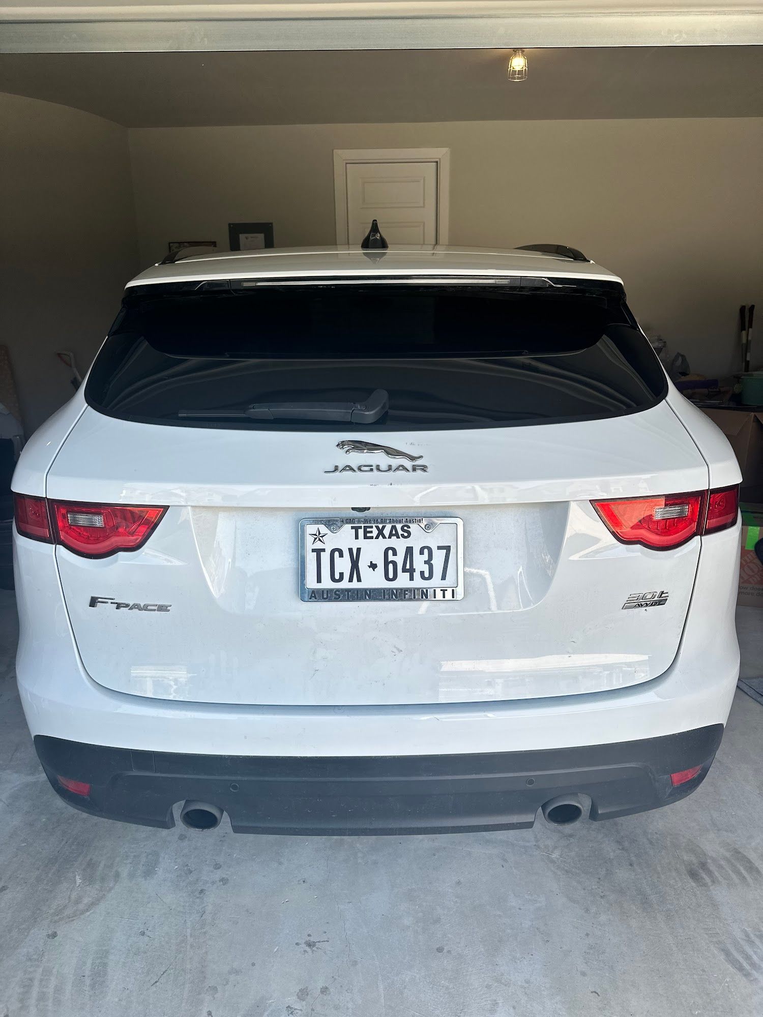 A white jaguar f pace is parked in a garage.