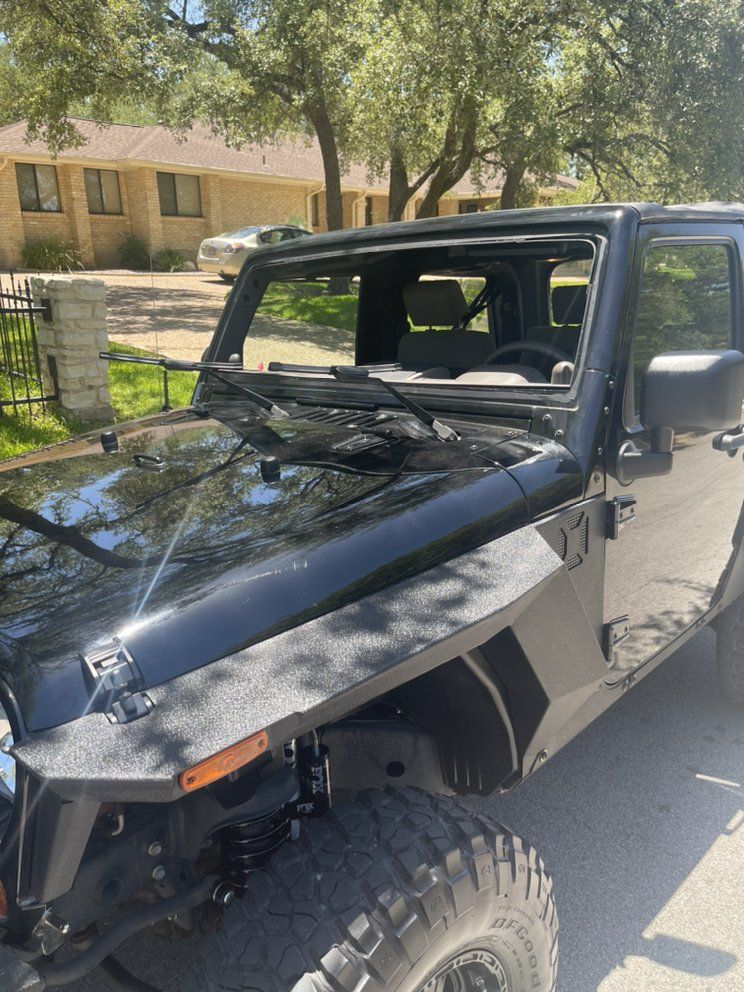 A black jeep is parked in front of a house.