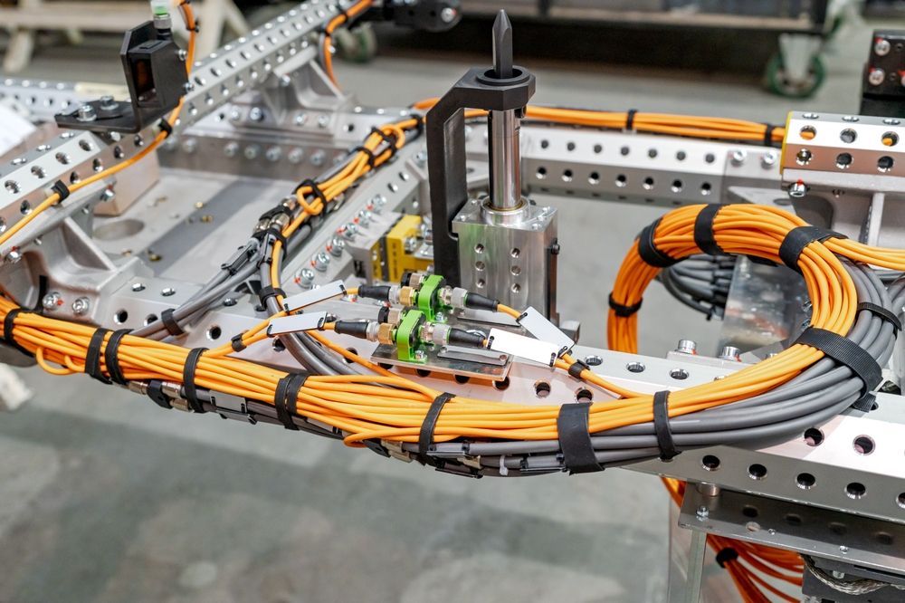 Industrial machine with orange cable harness on a metal frame in a workshop