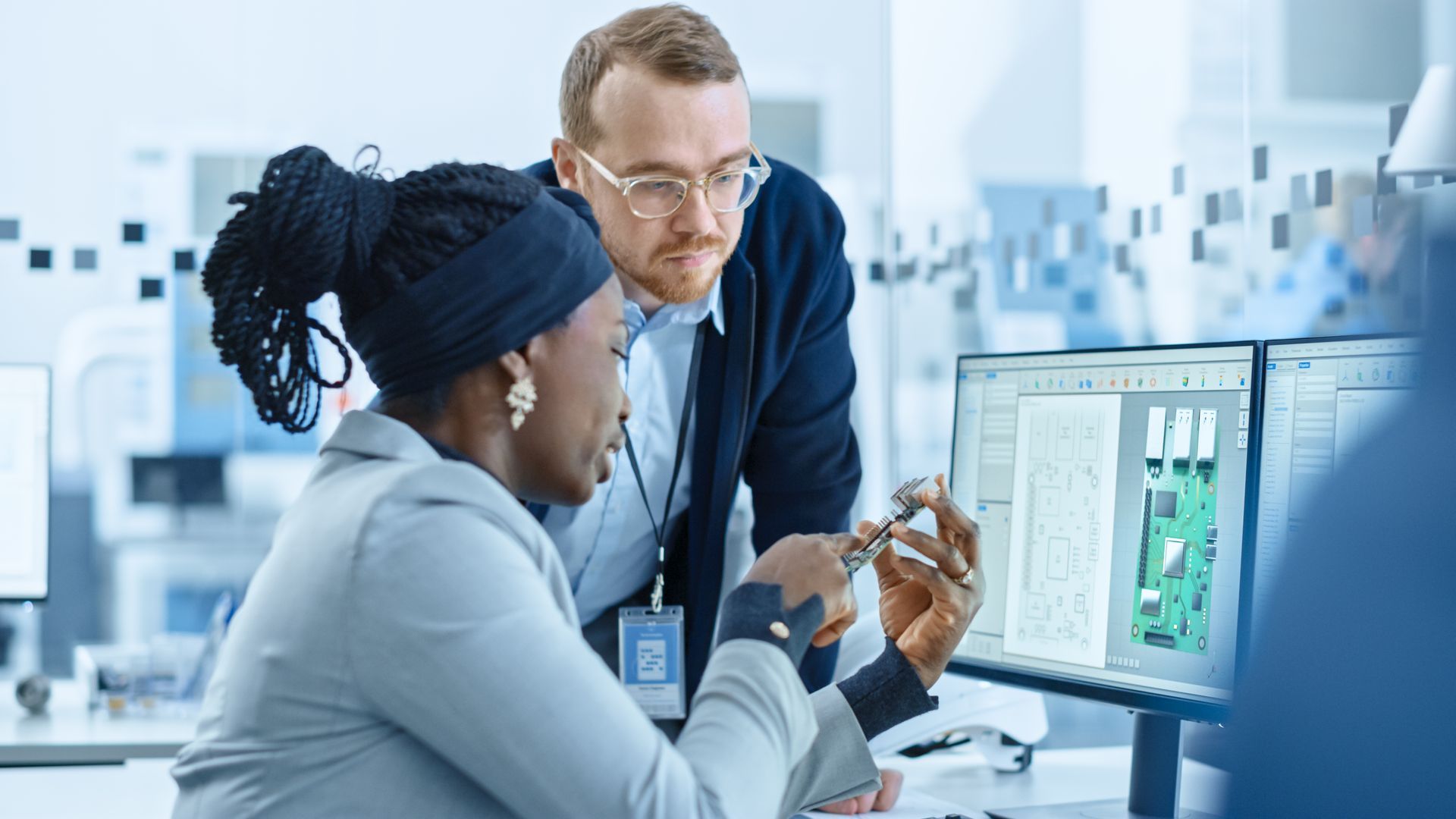 Two coworkers discussing data on a computer screen in a bright office