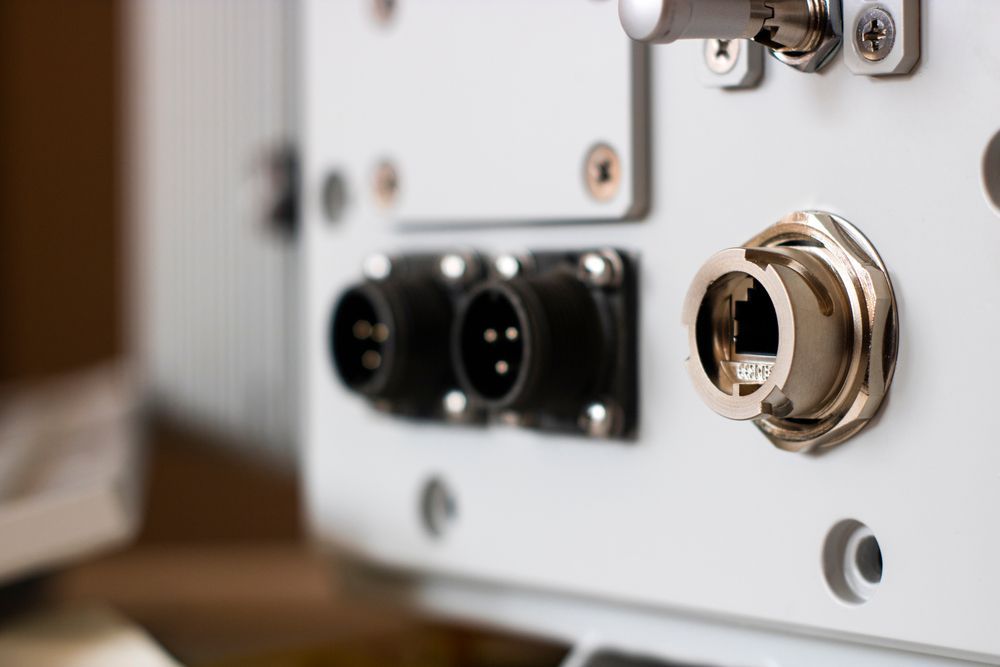 White equipment panel with two round black connectors and a shielded Ethernet port.