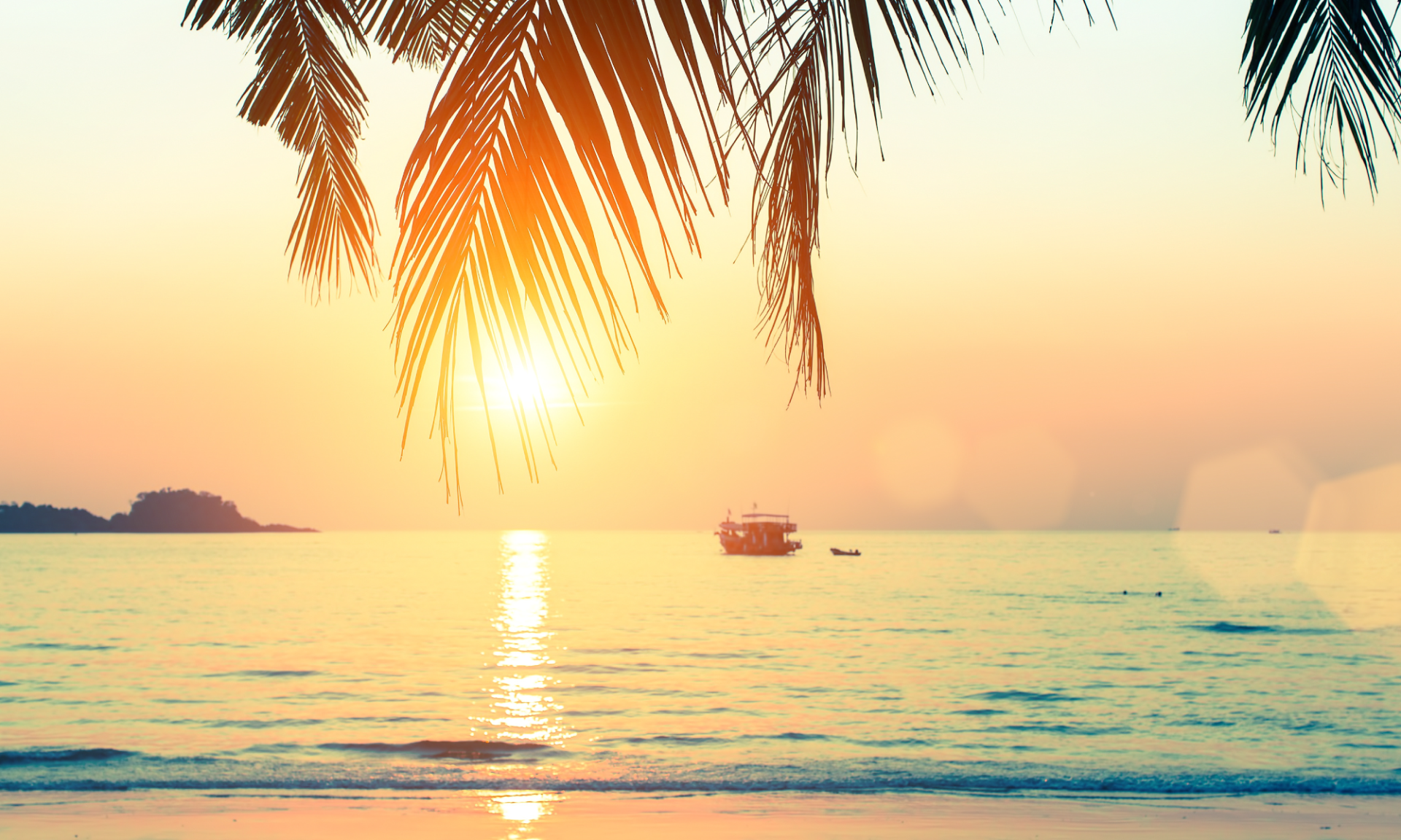 The sun is setting over the ocean with a boat in the distance.