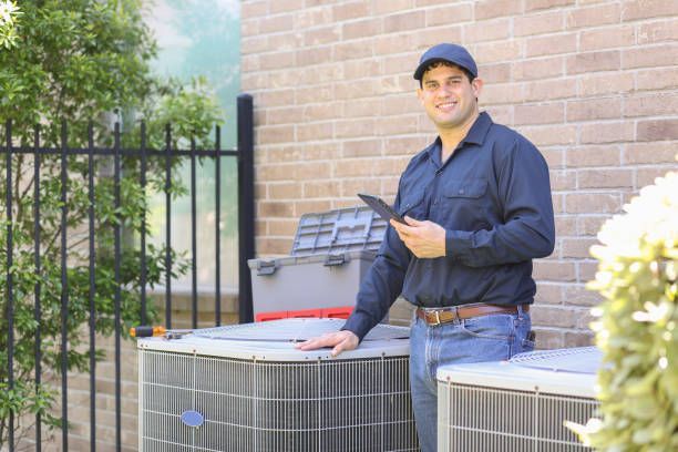 A man is standing next to two air conditioners and holding a tablet.