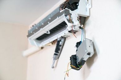 A close up of a broken air conditioner on a wall.