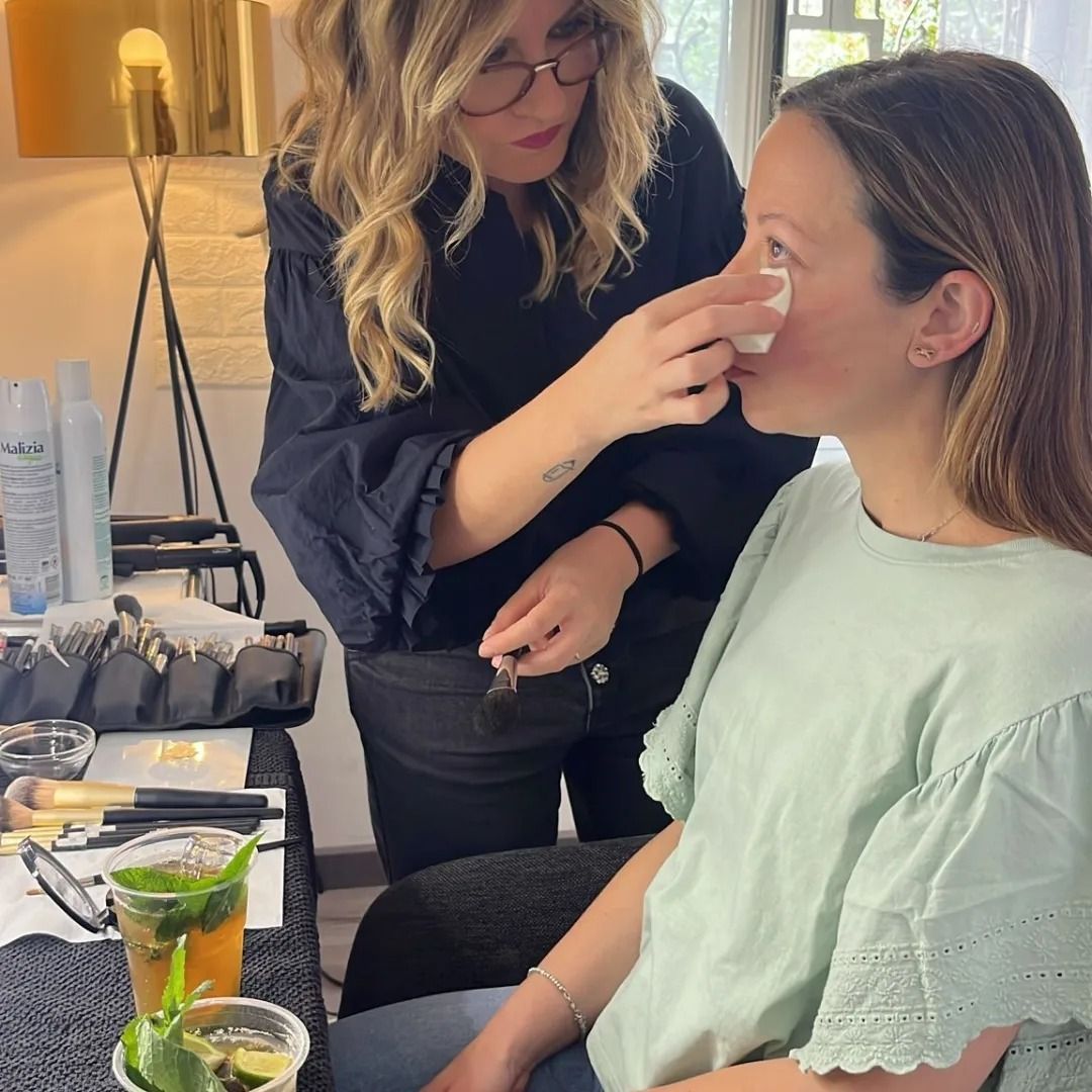 Truccatore che applica il trucco sul viso di una persona, in un ambiente chiuso.