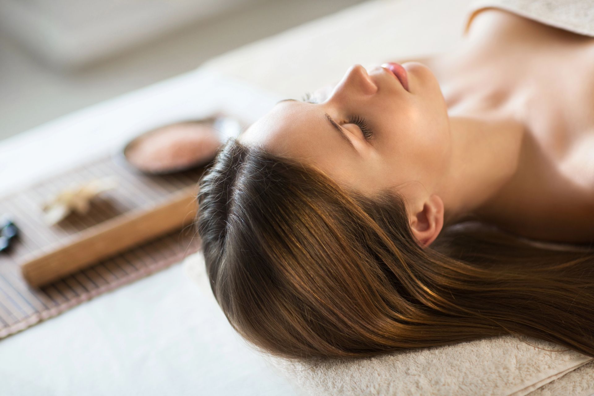 Donna che si tiene le mani a forma di cuore sopra l'addome, indossa un top bianco e pantaloni grigi.