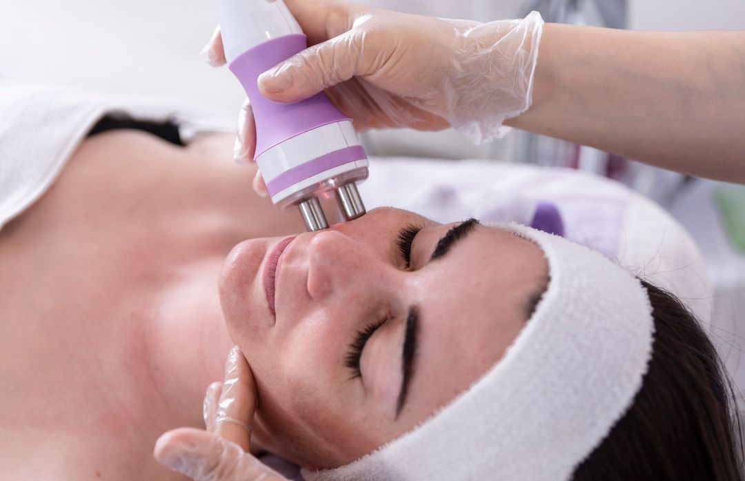 Persona che riceve un trattamento viso con un dispositivo portatile vicino al viso.