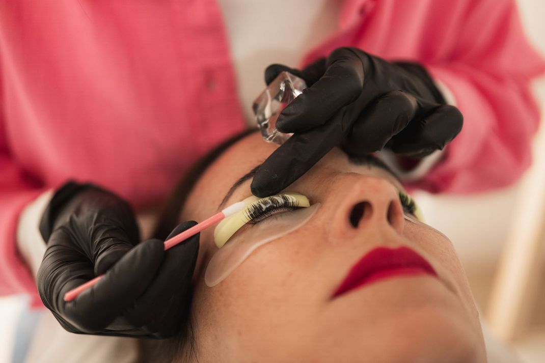 Una persona che si sottopone a un trattamento di laminazione delle ciglia. Un'estetista utilizza degli strumenti per incurvare le ciglia.
