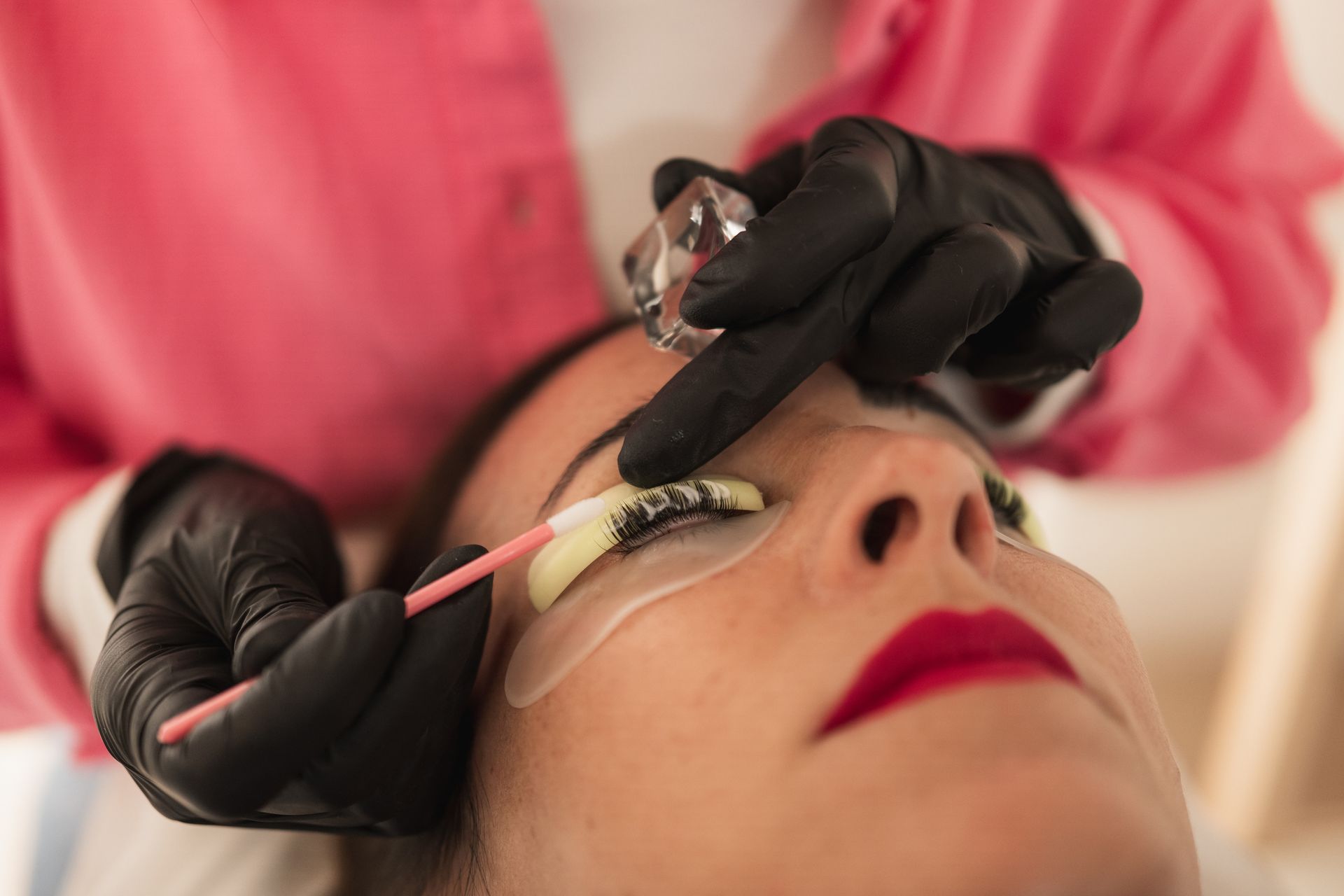 Una persona che si sottopone a un trattamento di laminazione delle ciglia. Un'estetista utilizza degli strumenti per incurvare le ciglia.