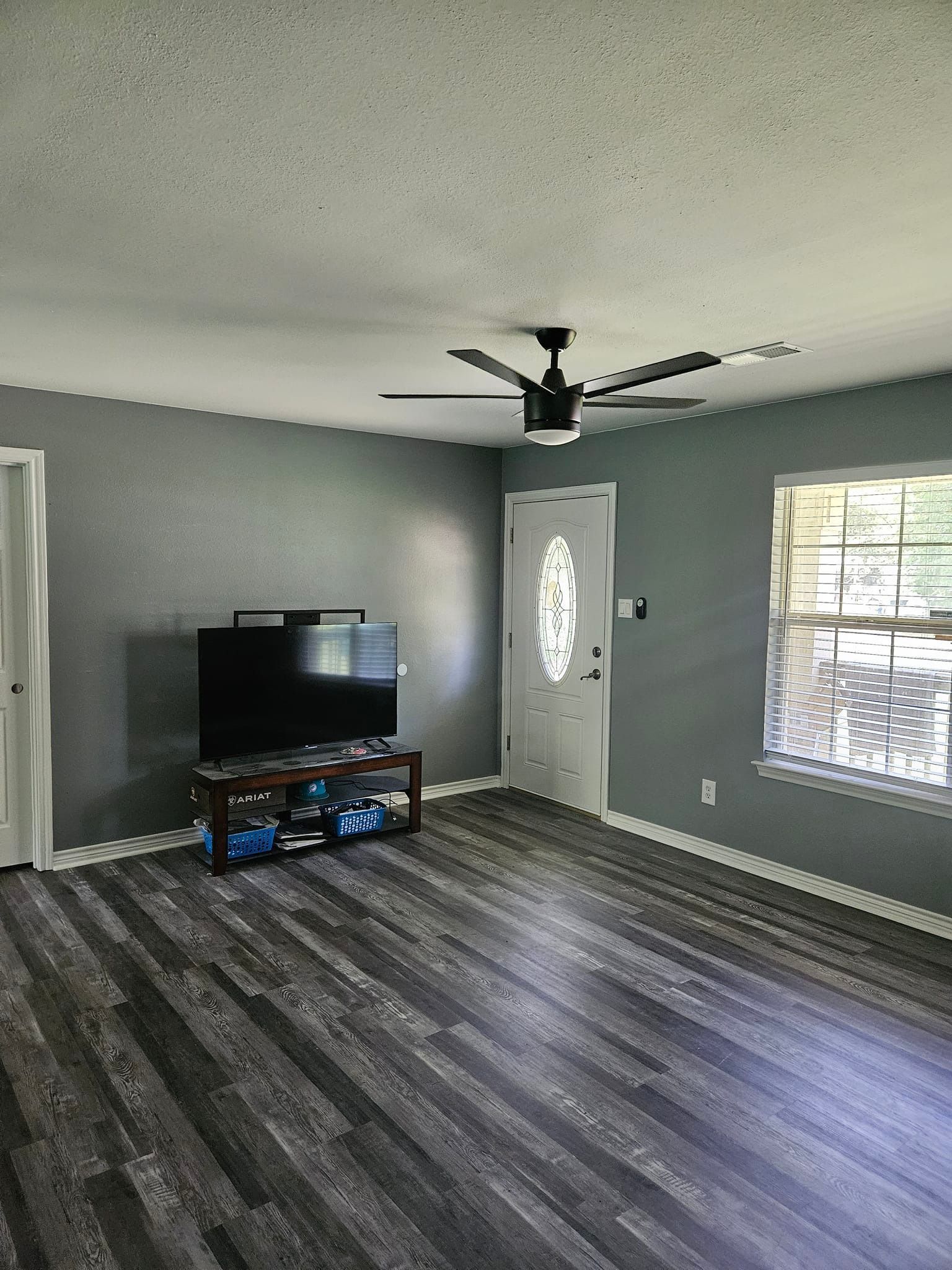 Woman in straw hat smiles, holding wine glass near a lake.