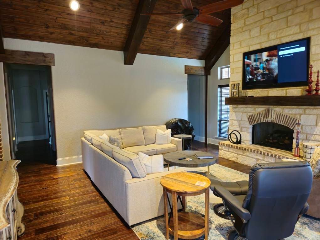 Woman in straw hat smiles, holding wine glass near a lake.
