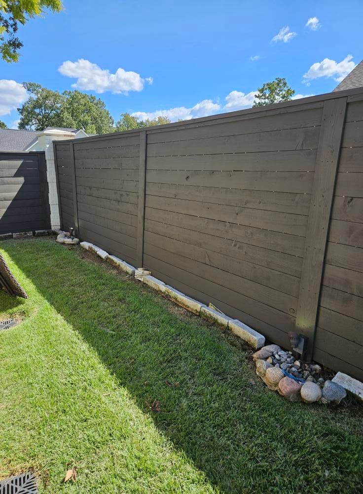 Woman in straw hat smiles, holding wine glass near a lake.
