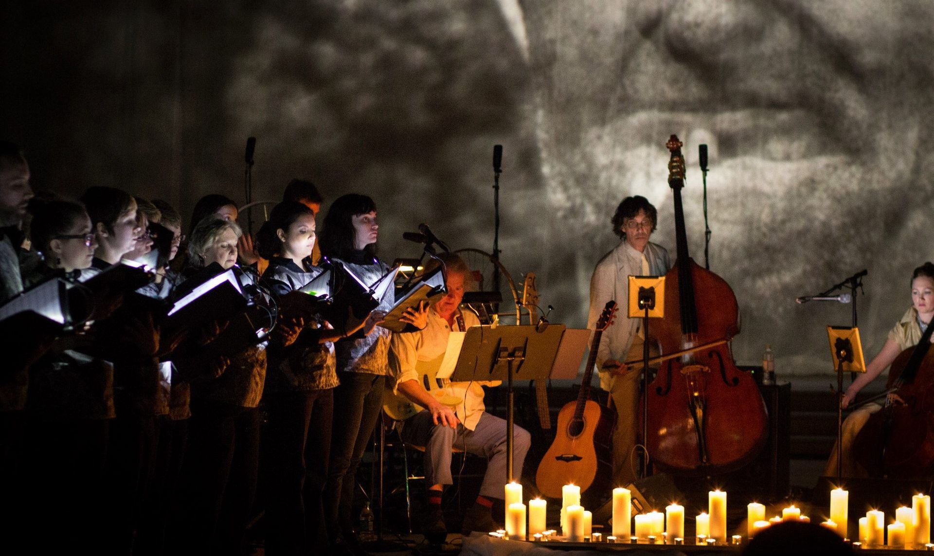 A group of people playing instruments on a stage with candles in front of them