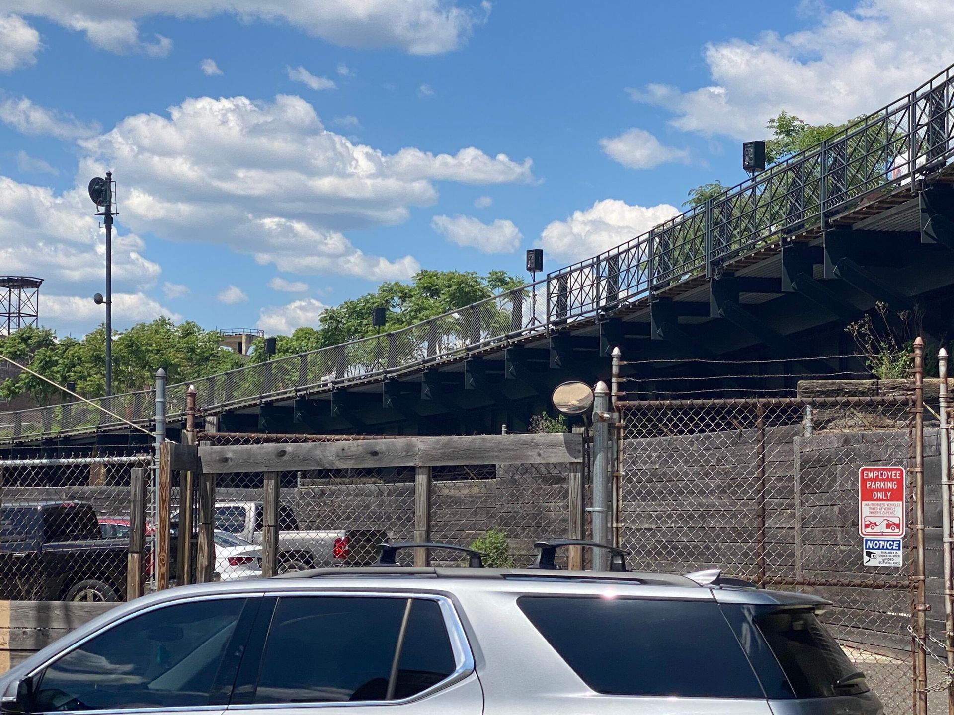 A silver suv is parked in front of a bridge.