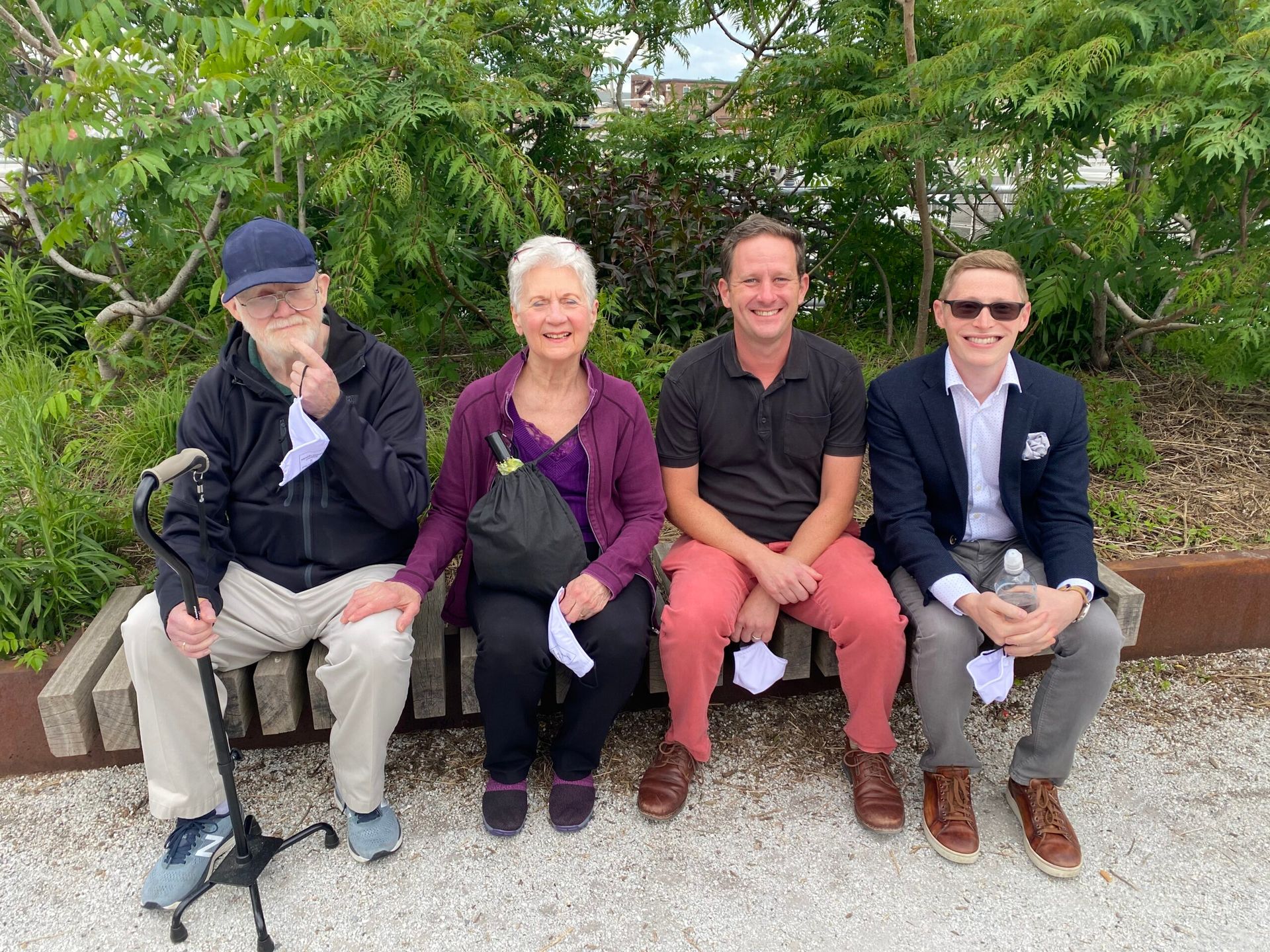 A group of people are sitting on a bench wearing face masks.