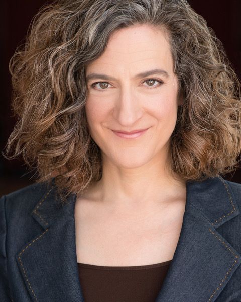 A woman with curly hair is wearing a blue jacket