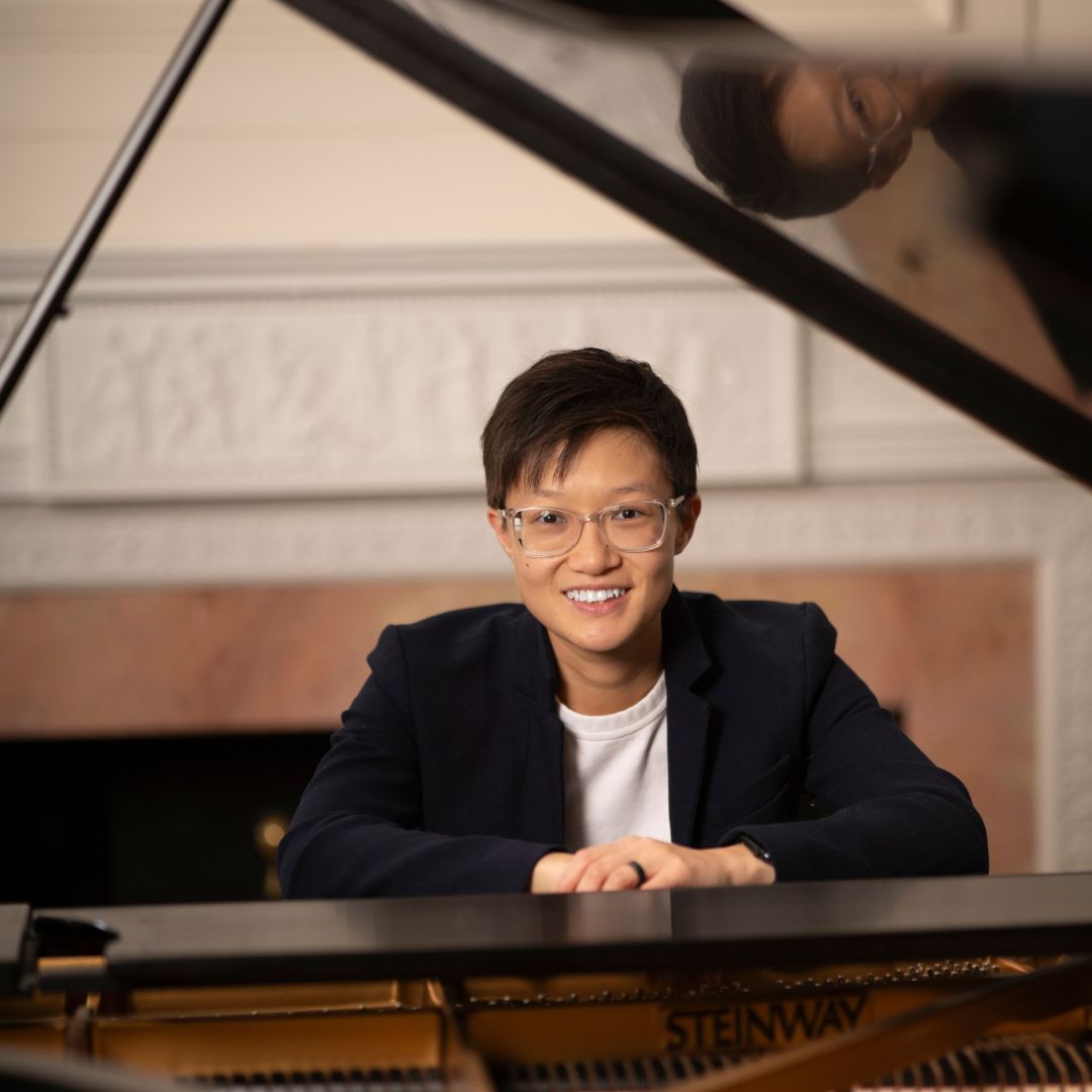 A woman wearing glasses and a blue jacket smiles for the camera