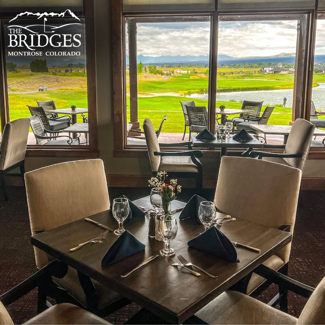 Restaurant interior with square tables set for dining, overlooking a golf course.