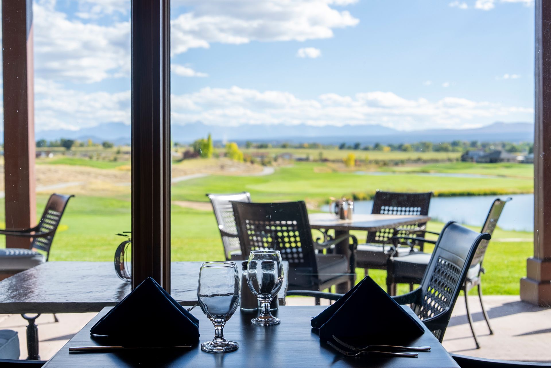 Restaurant table setting with view of golf course and mountains.