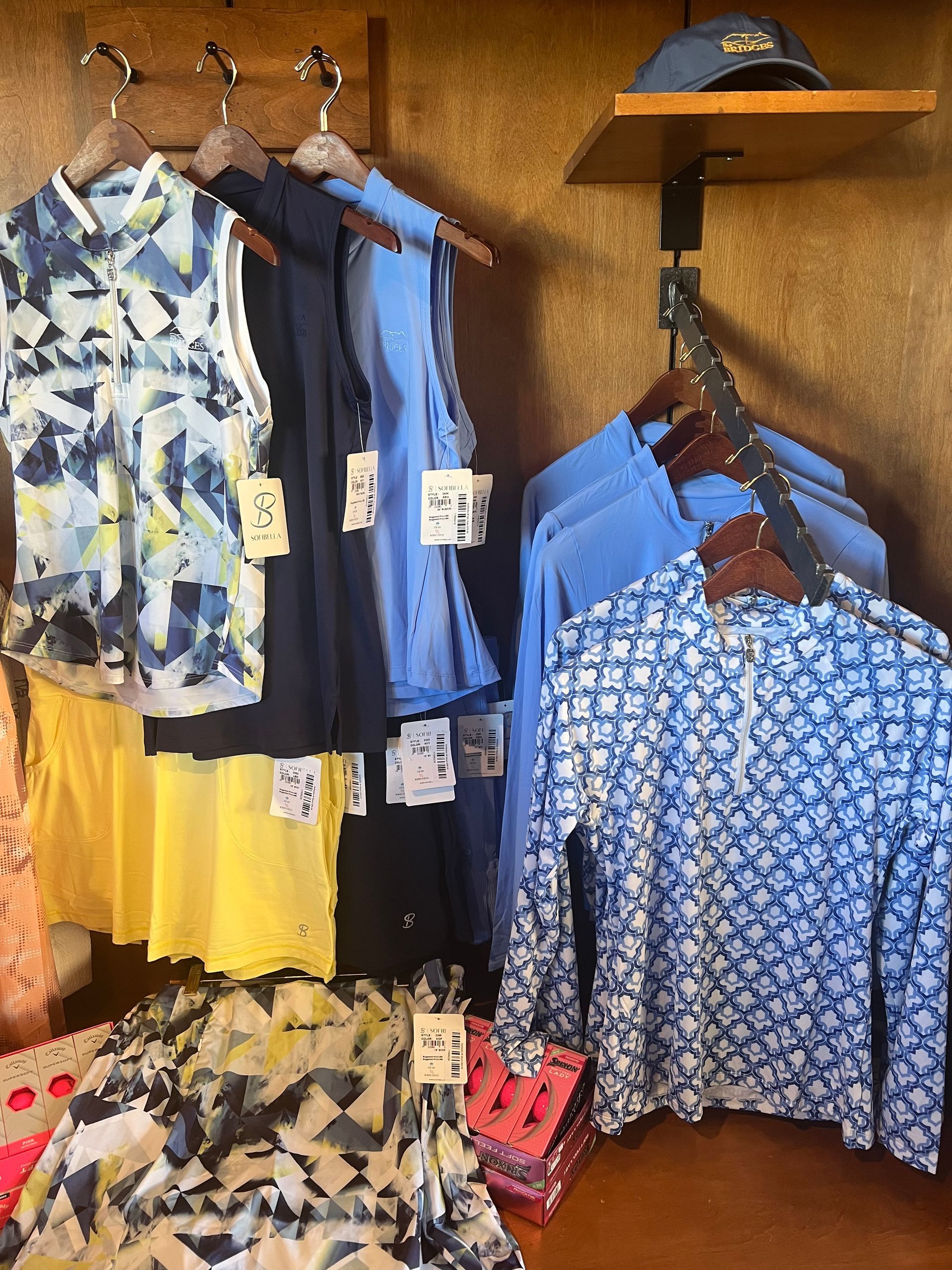 Clothing display with shirts in various colors and patterns on wooden hangers.