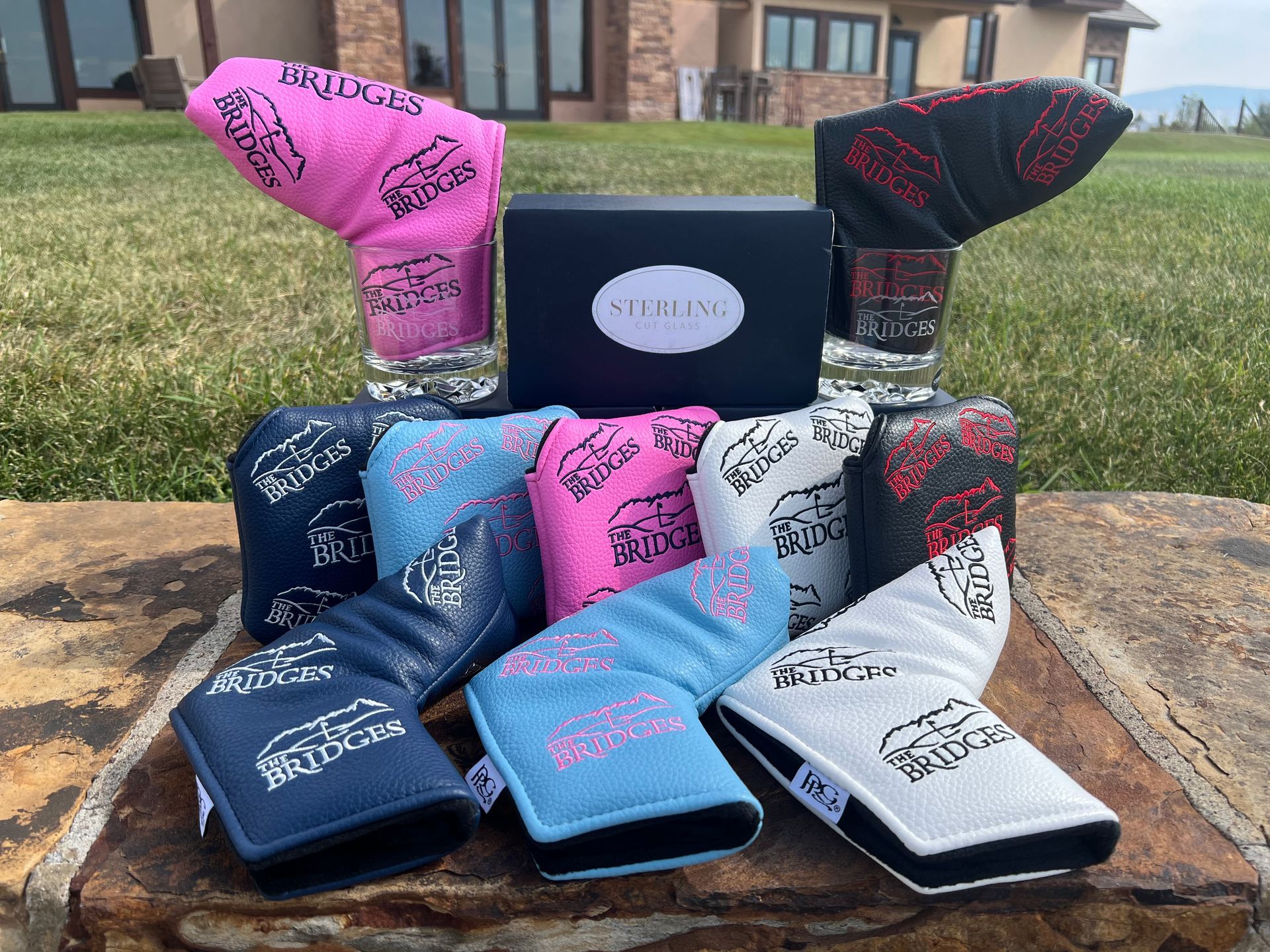 Golf putter headcovers in various colors, arranged on a stone surface.