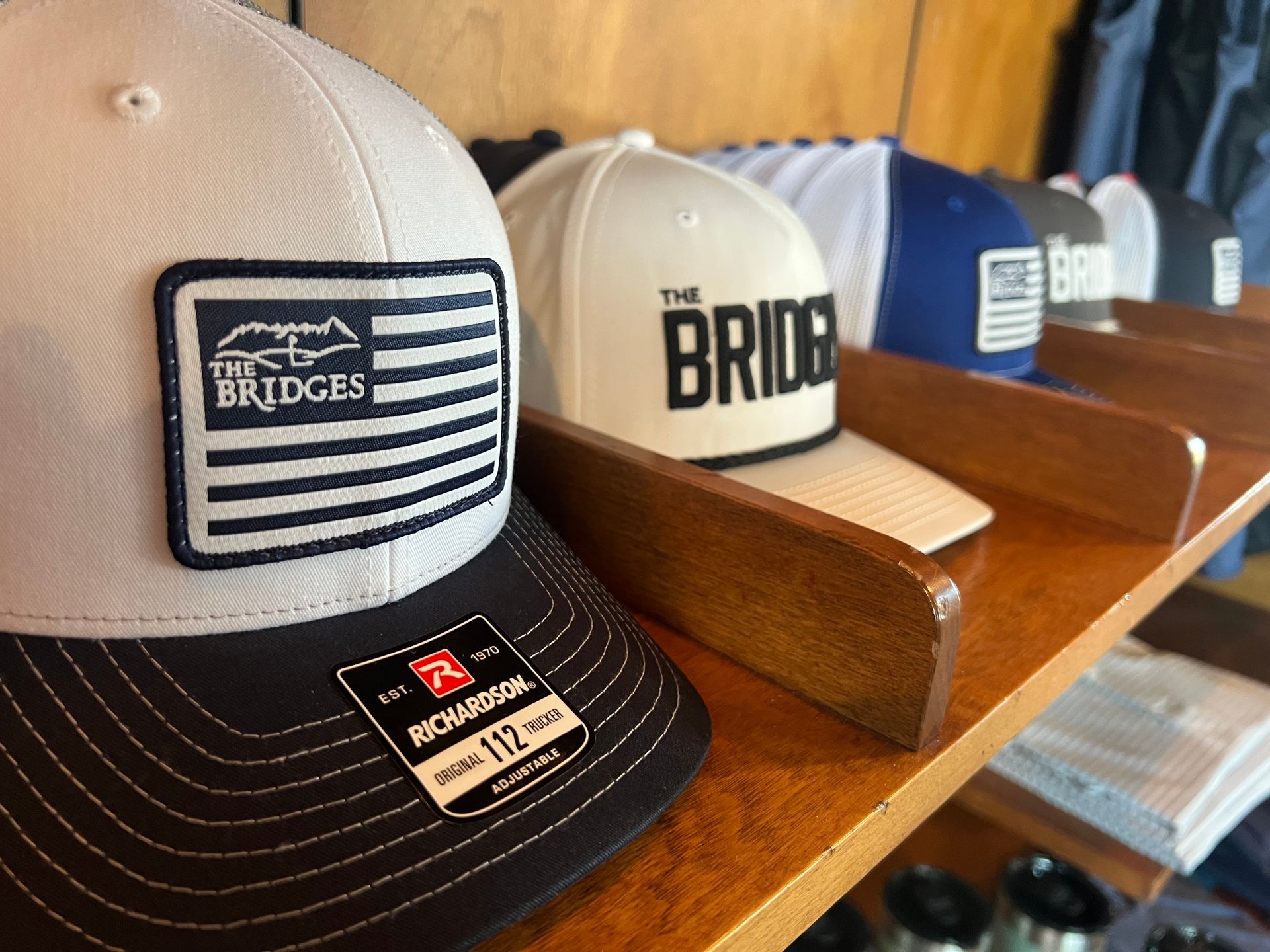 Hats displayed on a wooden shelf, various styles. One has 