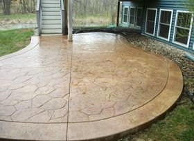 A concrete patio with a staircase in the background and a house in the background.