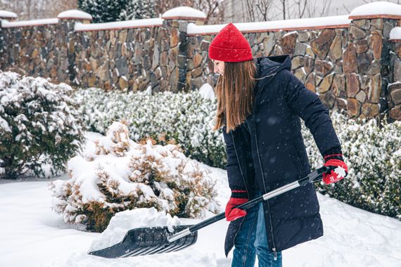 A woman removing snow from a residential property.