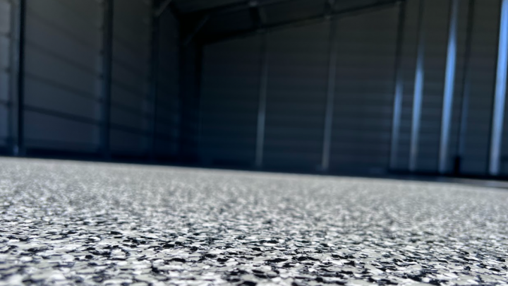 A close up of a garage floor with a black wall in the background.
