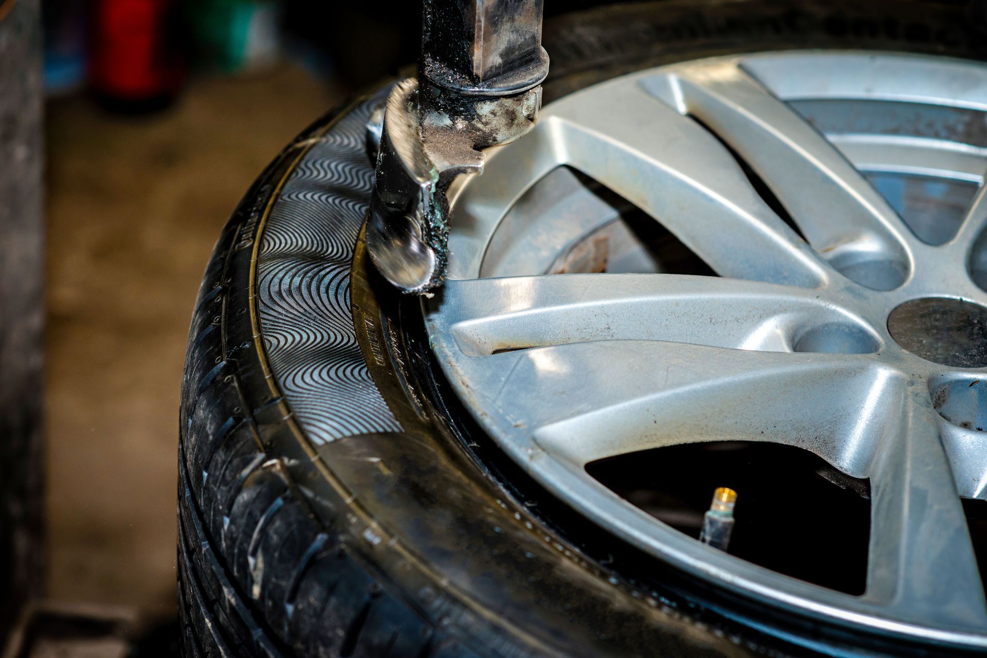 A person is changing a tire on a car in a garage.