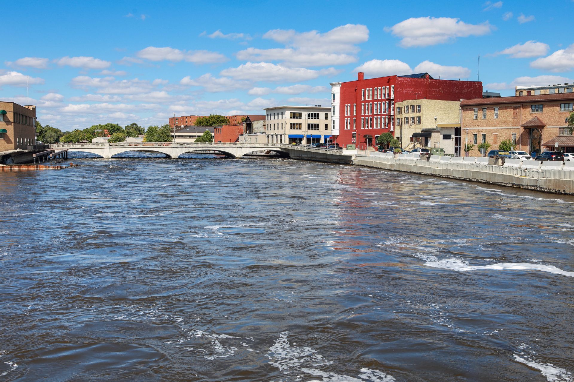 Three roofers in neon green vests installing tiles on a partially completed orange tile roof.