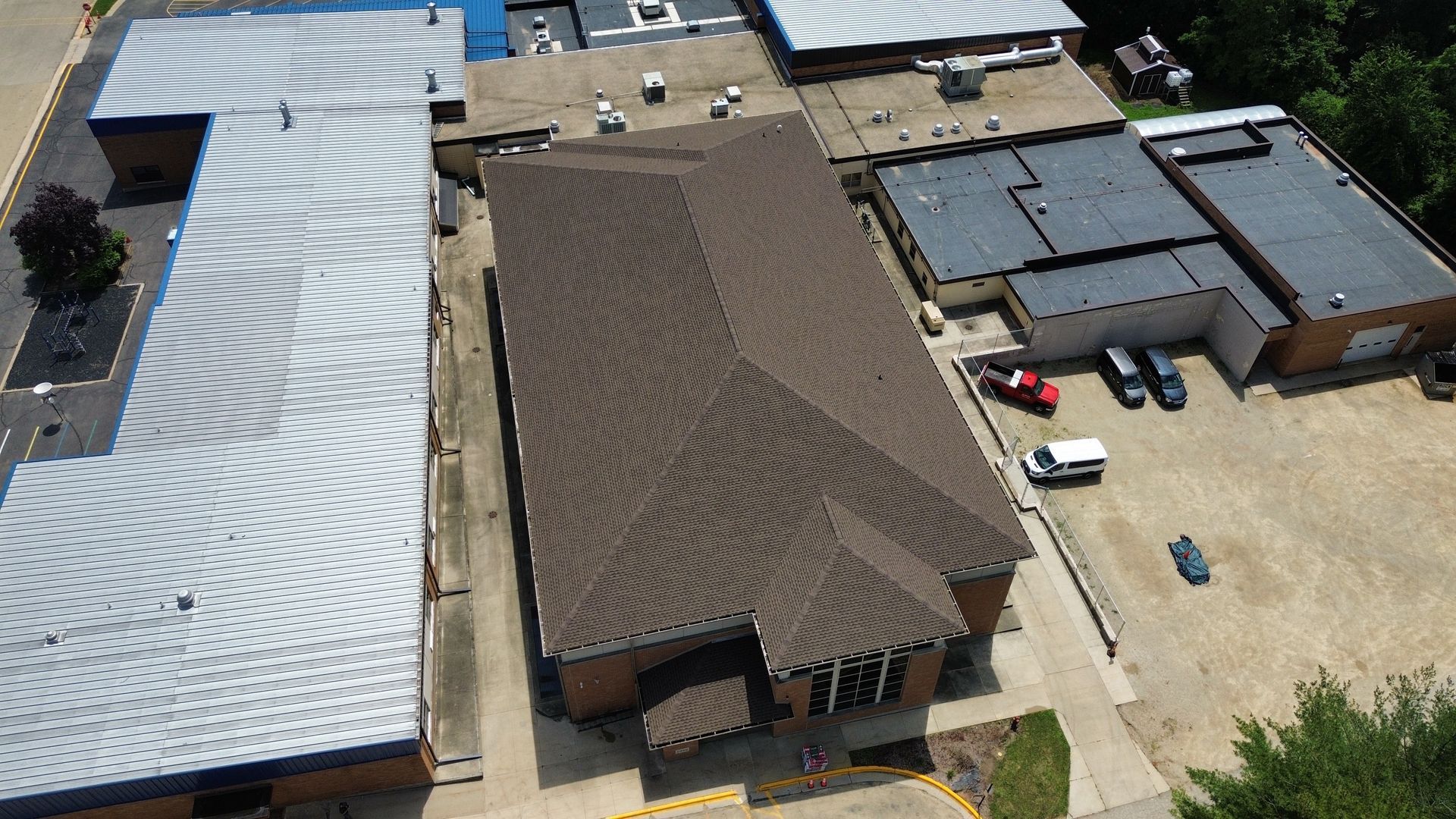 High-angle view of a brown-roofed building and surrounding parking area with vehicles.