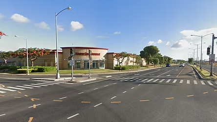 A street with a crosswalk and a building in the background.