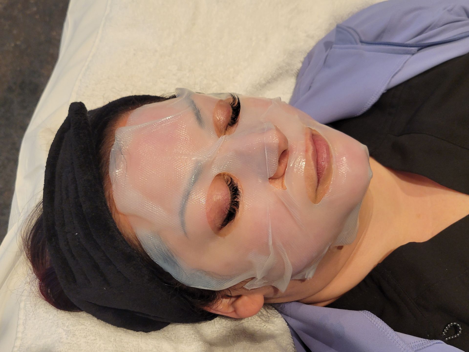 A woman is laying on a bed with a mask on her face.