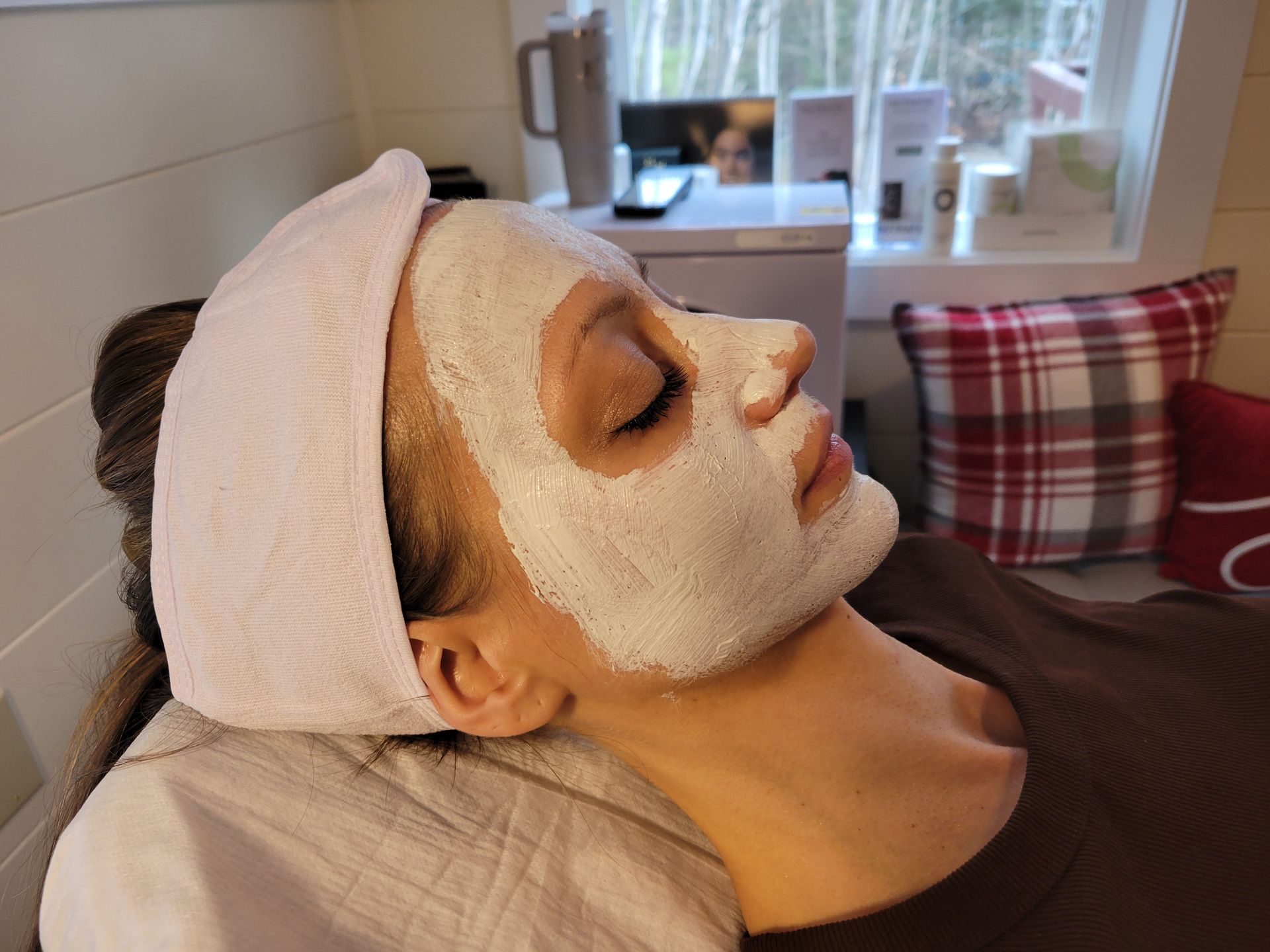 A woman is laying down with a white mask on her face