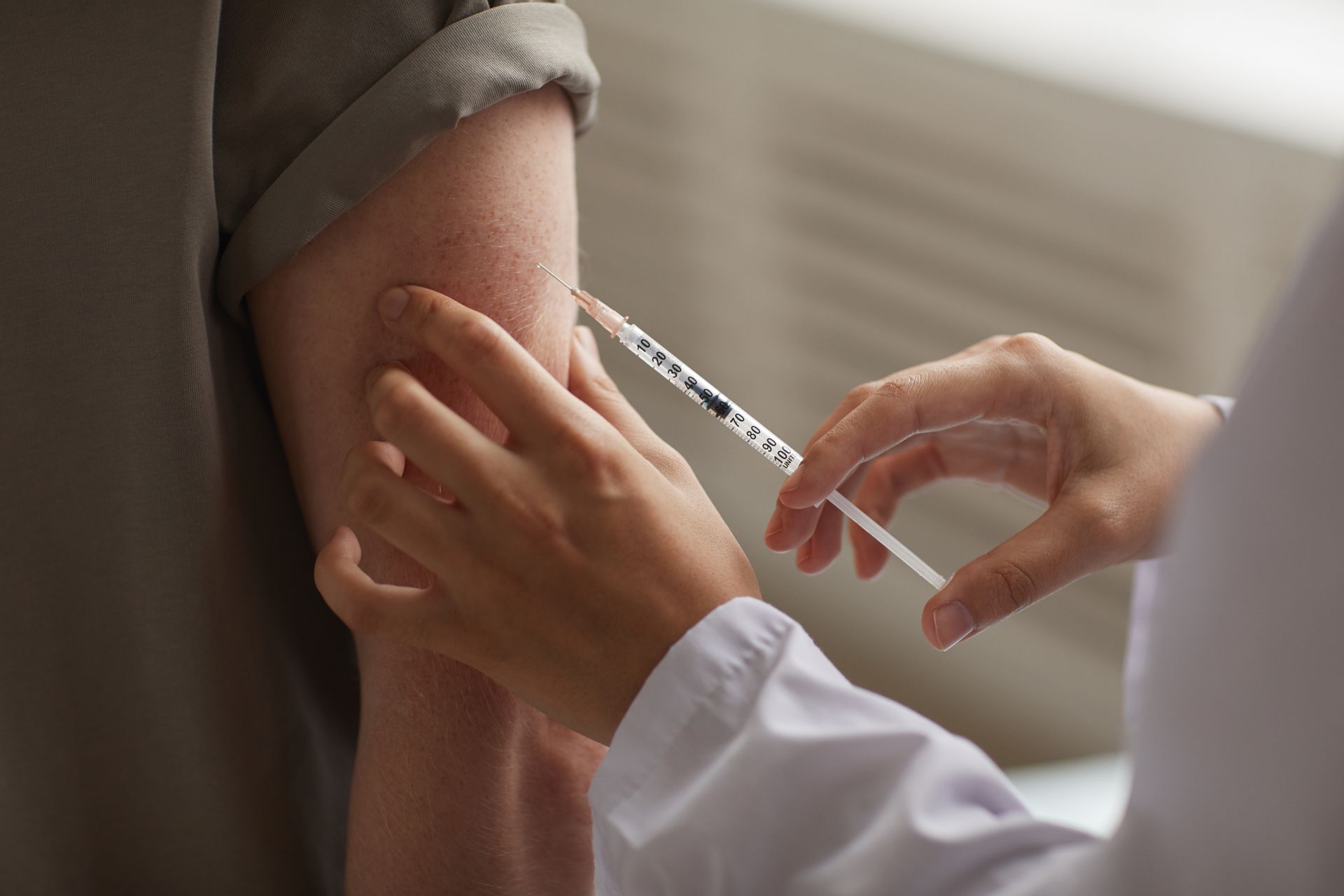 Person receiving an injection in their upper arm by a healthcare worker.
