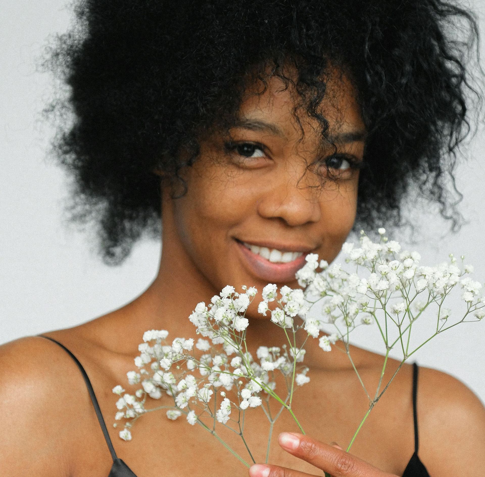 A woman with curly hair is holding a bunch of baby 's breath flowers.